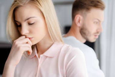 selective focus of upset girl standing near boyfriend, relationship difficulties concept  clipart