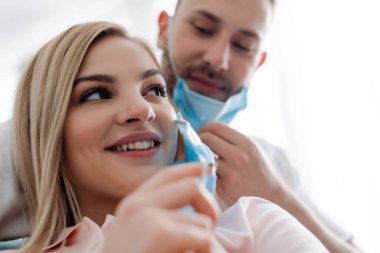 Evde tıbbi maskeli mutlu kadın ve erkeğin seçici odak noktası