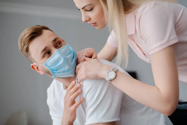 Hermosa Chica Tocando Frustrado Hombre Máscara Médica Casa — Foto de Stock