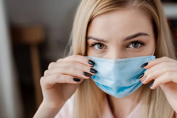 Junge Frau Blickt Kamera Während Sie Medizinische Maske Berührt — Stockfoto