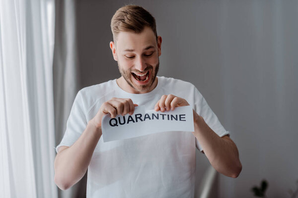 excited man ripping paper with quarantine lettering 