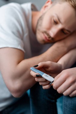 Hamilelik testinin seçici odak noktası. Bu da üzgün bir adamın yanındaki kadında negatif sonuçlar doğuruyor. 