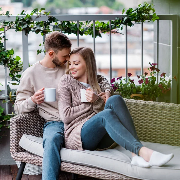 幸せな男と陽気な女がお茶を持って屋外のソファに座って — ストック写真