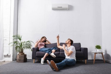 Evde uzaktan kumandalı, bozuk klimalı üzgün bir çift. 