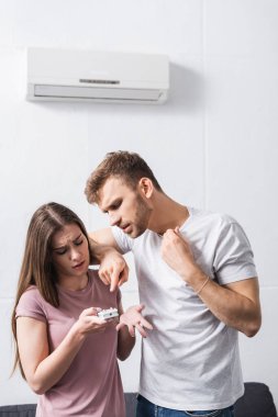 young couple suffering from heat at home with broken air conditioner  clipart