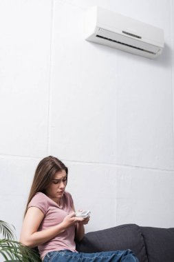 Klimayı açmaya çalışırken sıcaktan muzdarip şüpheli bir kadın.