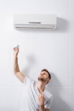 sad man feeling uncomfortable with broken air conditioner at home during summer heat  clipart