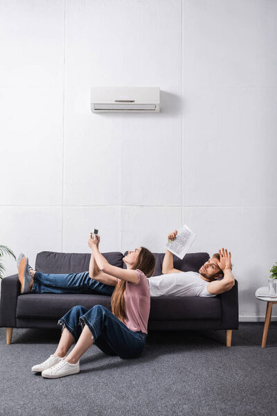 angry couple suffering from heat while sitting home with broken air conditioner 