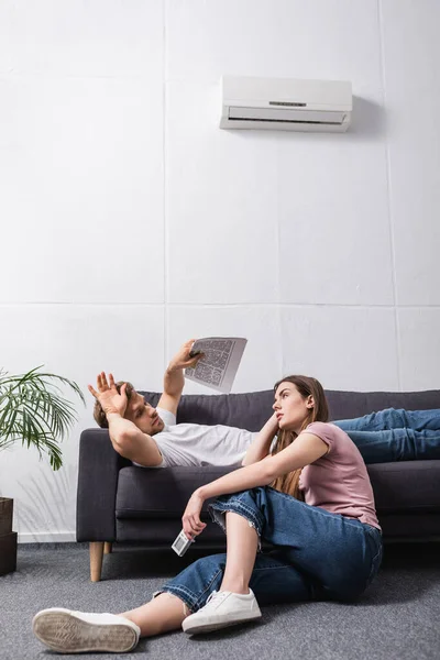 Triste Casal Com Controlador Remoto Sofrendo Calor Casa Com Condicionado — Fotografia de Stock