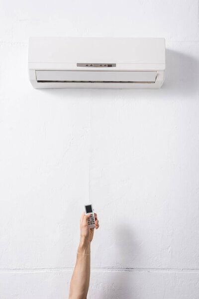 cropped view of male hand holding remote controller from air conditioner