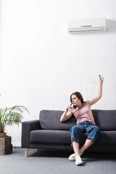 Jovem Mulher Bebendo Água Enquanto Sofre Calor Tentando Ligar Condicionado — Fotografia de Stock