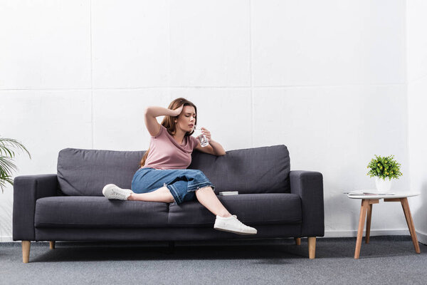 exhausted woman drinking water while suffering from heat at home