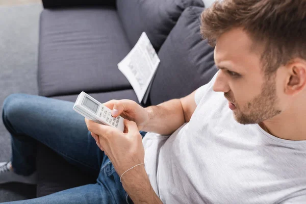 Angry Man Trying Switch Air Conditioner Remote Controller Home — Stock Photo, Image