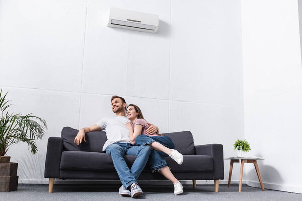 happy girlfriend and boyfriend hugging at home with air conditioner
