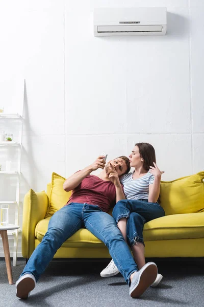 Young Confused Couple Remote Controller Suffering Heat Home Broken Air — Stock Photo, Image