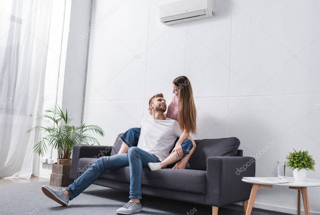 happy emotional couple hugging at home with air conditioner
