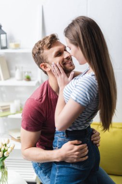 Gülümseyen romantik genç çift evde sarılıyorlar.