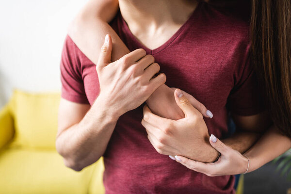 cropped view of young couple hugging at home