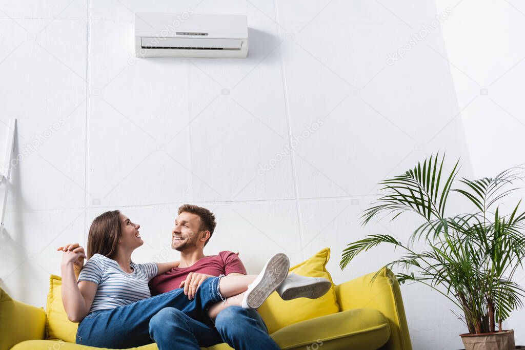Happy young couple hugging at home with air conditioner