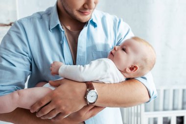 Genç gülümseyen bir adamın elinde sevimli bir erkek çocuğu tuttuğunu gördüm.