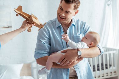 Babamın yanında oyuncak uçak tutan çocuğun küçük şirin kardeşini tutuşu.