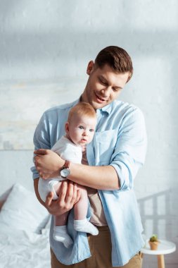 Mutlu baba yatak odasında kucağında sevimli bir bebek tutuyor.