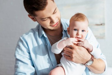Babanın elleri üzerinde otururken el ele tutuşan tatlı çocuk.
