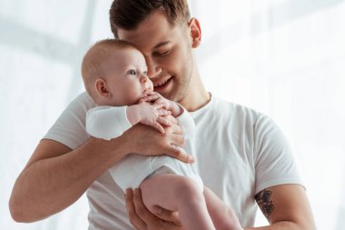 Mutlu bir baba kucaklıyor ve sevimli gözleri kapalı bir çocuğu kucaklıyor.