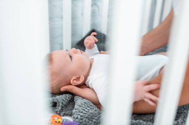 Erkeğin bebek karyolasında uzanan sevimli çocuğa dokunuşunu, seçici bir odak noktası.