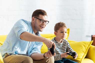 KYIV, UKRAINE - 9 Haziran 2020: heyecanlı baba ve ilgili oğul joysticklerle video oyunu oynuyor