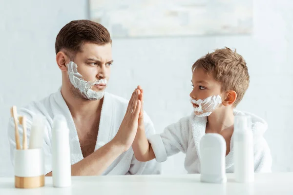 认真的父亲和儿子 剃须泡沫对高达5分的脸的选择性聚焦 — 图库照片