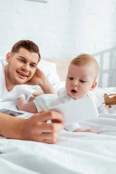 Enfoque Selectivo Sonriente Padre Tomando Selfie Teléfono Inteligente Con Adorable — Foto de Stock