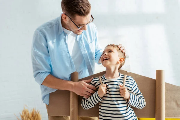 Happy Father Touching Head Cheerful Son Cardboard Plane Wings Back — Stock Photo, Image