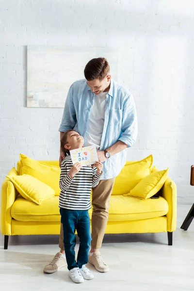 Adorable Boy Looking Father While Holding Handmade Fathers Day Greeting — Stock Photo, Image