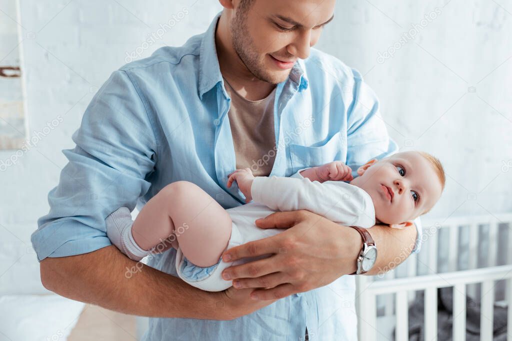 cute baby boy looking away on hands of happy father