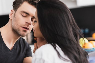 Yakışıklı bir adamın mutfakta güzel bir sevgiliye dokunuşunun seçici odağı. 