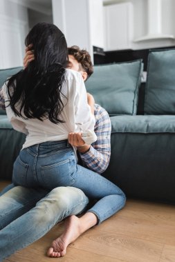 Erkek oturma odasında öpüşüyor ve seksi kız arkadaşını kucaklıyor.