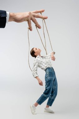 cropped view of puppeteer holding marionette on strings isolated on grey clipart