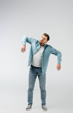 Gri renkte izole edilmiş kukla gibi poz veren genç adam