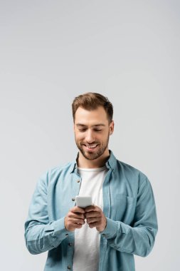 Gri renkte akıllı telefon kullanan gülümseyen genç adam.