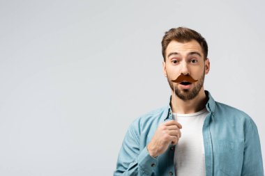 Şok olmuş, takma bıyıklı genç bir adam griye saplanmış bir sopa.