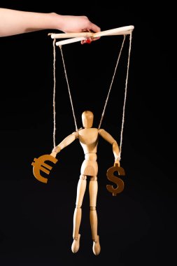 cropped view of puppeteer holding wooden marionette on strings with currency signs isolated on black clipart