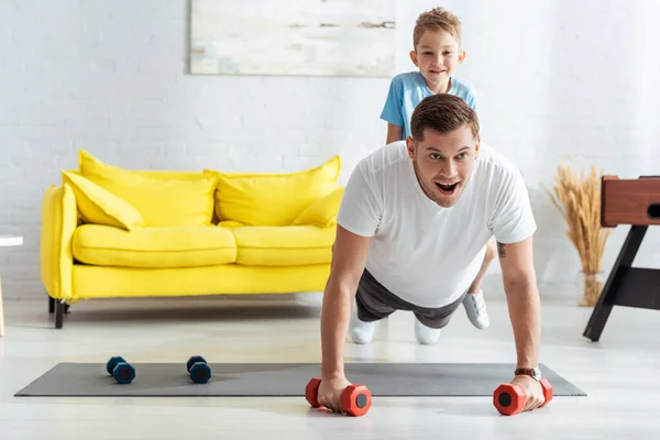 Young Man Doing Push Ups Dumbbells While Son Sitting His — Stock Photo, Image