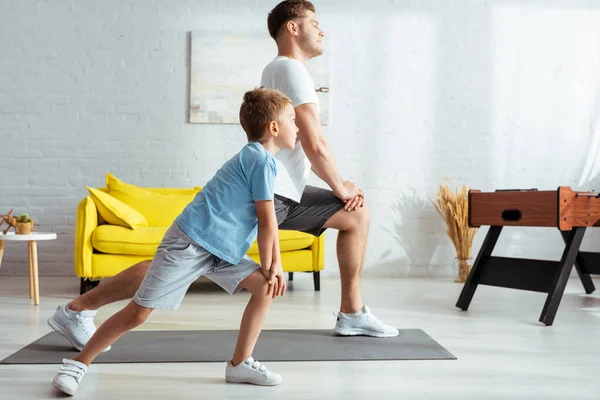 Vista Lateral Pai Jovem Filho Bonito Fazendo Lunges Enquanto Exercita — Fotografia de Stock