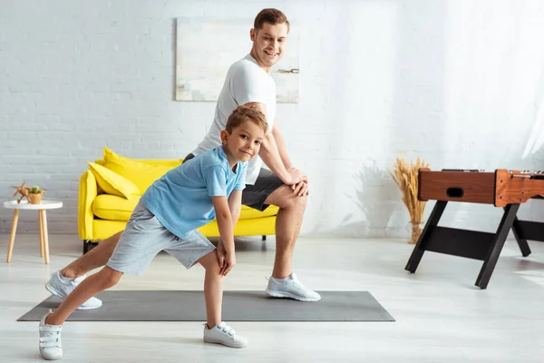 快乐的父亲和儿子在家里锻炼的时候突然跳起来 — 图库照片