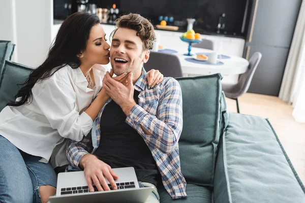 Selective Focus Attractive Girl Kissing Cheerful Boyfriend Using Laptop Couch — Stock Photo, Image