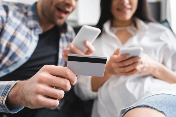 Selective Focus Positive Man Holding Credit Card While Using Smartphone — Stock Photo, Image