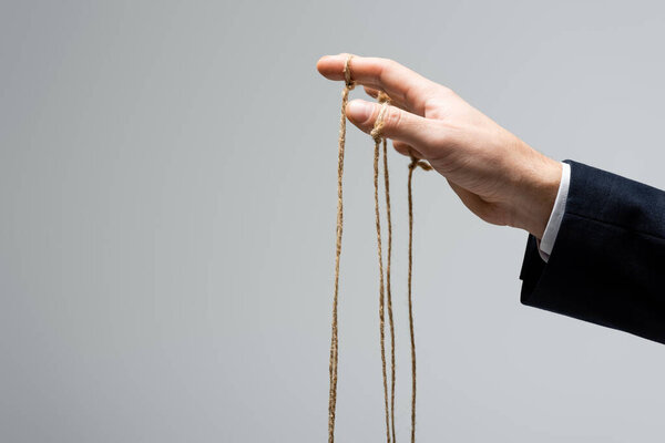 cropped view of puppeteer with strings on fingers isolated on grey