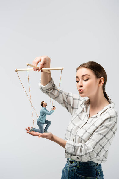 female puppeteer kissing male marionette with ring box isolated on grey