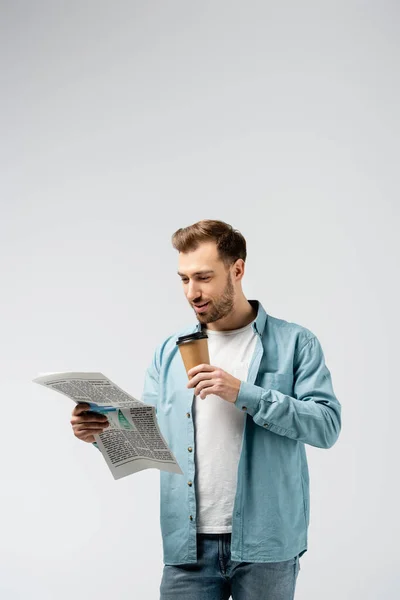 Junger Mann Liest Zeitung Und Trinkt Kaffee Isoliert Auf Grau — Stockfoto